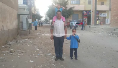 بنته الصغيرة على كتفه والتانية في إيده.. أب يوصل ابنته الصغيرة للمدرسة بأول أيام الدراسة بكفر الشيخ